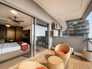 a bedroom with a bed and a balcony with chairs at Mulberry Homes Supernova in Noida