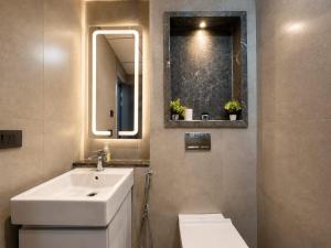 a bathroom with a sink and a toilet and a mirror at Mulberry Homes Supernova in Noida +258 photos