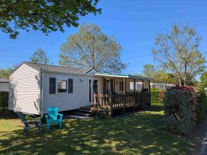 a white tiny house with a blue chair in the yard at Camping Le Ragis in Challans