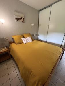 a bedroom with a large yellow bed in a room at Albizias 3 in Eugénie-les-Bains