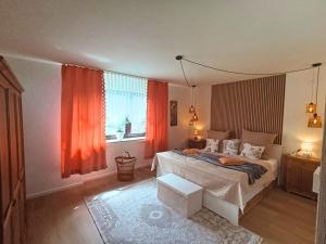 a bedroom with a bed and a window with orange curtains at EifelRuhe 5 - Platz für bis zu 8 Personen, Hunde willkommen in Schleiden