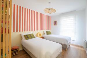 a bedroom with two beds and a striped wall at Bright House between Ocean and Golf in Moliets-et-Maa