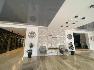 a lobby with chairs and a clock on a wall at Hotel Unirea in Mamaia