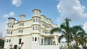 a large white building with a clock tower at Marudhar Resort in Chittaurgarh