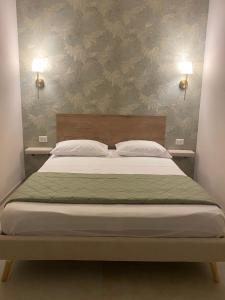 a bed in a bedroom with two lights on the wall at L altra Volta in San Pietro Vernotico