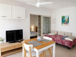 a living room with a bed and a table and a television at L'Eden in Ansouis