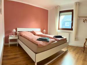 a bedroom with a bed with pink walls and a window at Eifel Moments in Kall
