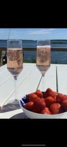 two champagne glasses with a bowl of strawberries on a table at Bryggstuga med privat bastu in Norrtälje