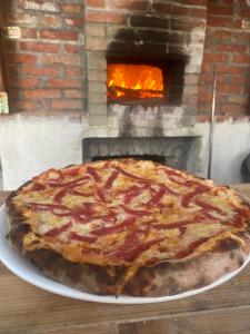 a pizza on a plate in front of a brick oven at Meti Guest House in Krujë