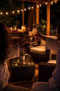two people holding glasses of wine on a patio at night at Ô Temps Des Pins in Éguilles