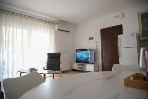 a living room with a television and a table and chairs at Meltemi by GG in Alexandroupoli