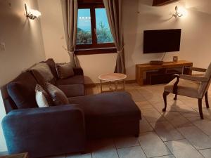 a living room with a couch and a tv at Gîte des Charbonneaux in Avrée