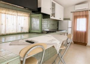a kitchen with a table with chairs and a refrigerator at Monolocale in un piccolo paradiso in Tramatza