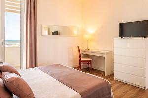 a hotel room with a bed and a desk with a television at Hotel Esplanade in Marina di Pietrasanta