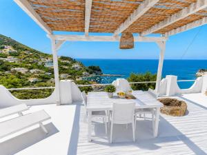 a white dining room with a view of the ocean at Maridea - Vela in Ponza