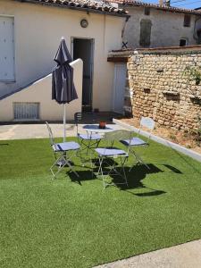 a table and chairs and an umbrella on a lawn at Maison d'hôtes du Faubourg Charrault Saint Maixent L'Ecole in Saint-Maixent-lʼÉcole
