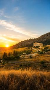 a sunset in a field with a building in the background at Nel cuore di Segesta in Calatafimi