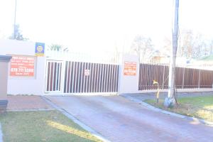 a white building with a fence and a tree at Prax Guest House Benoni in Benoni +2 photos