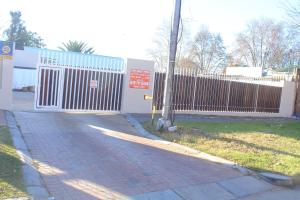 a fence in front of a building with a sidewalk at Prax Guest House Benoni in Benoni