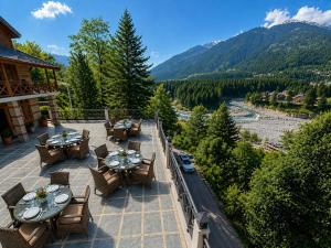 an outdoor patio with tables and chairs and a mountain at Hotel Hollywood Manali - Scenic River & Mountain View With Premium Rooms Near Mall Road in Manāli