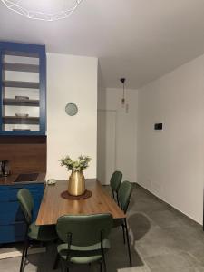 a kitchen with a wooden table and green chairs at BR Tale in Lezhë