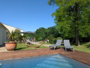 two chairs and a hammock next to a pool at l'Orée du Bois in Saint-Brice