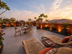 a patio with tables and chairs on a roof at Abode Jaipur in Jaipur