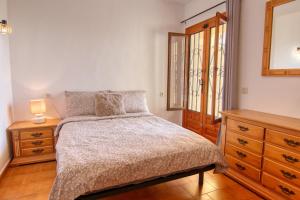 a bedroom with a bed and a dresser and a mirror at Casa Morendo in Teulada +9 photos