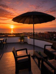 a patio with an umbrella and chairs and a table at Cactus Apartment - Walk to Surf Beaches, Rooftop View, Remote Work, Free Parking, AC in Agadir nʼ Aït Sa