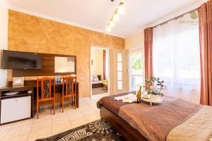 a bedroom with a bed and a desk and a television at GRAND VILLA USTKA- POKOJE z BALKONAMI I TARASAMI, PARKING W CENIE ! in Ustka