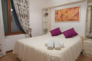 a bedroom with a white bed with purple pillows at Appartamento Monte Ladu in Porto Rotondo