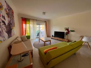 a living room with a green couch and a television at Vilamoura TOP MouraPraia in Vilamoura