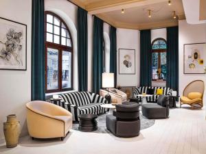 a lobby with chairs and tables and windows at Rezydent Hotel Sopot - MGallery Collection in Sopot