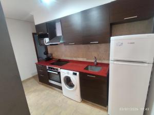 a kitchen with a white refrigerator and a washing machine at BAKEA in Bermeo