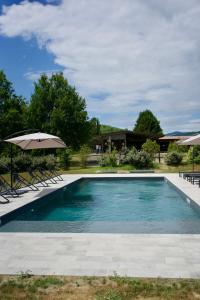 a swimming pool with chairs and an umbrella at Origine Country Farm in Tabiano