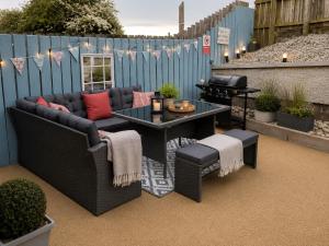 a patio with a couch and a table and a grill at Grovehouse in Portstewart
