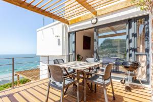 a dining room with a table and chairs on a balcony at Beachfront Bliss in Cape Town