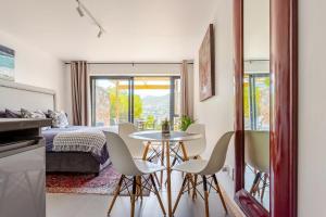 a room with a bed and a table and chairs at Beachfront Bliss in Cape Town