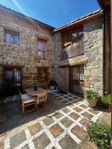 a patio with a table and chairs in front of a building at La Casuca De la Iglesia in Ubiarco