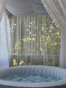 a tub in front of a window with a curtain at Vikendica Cokori - private pool and jacuzzi in Banja Luka