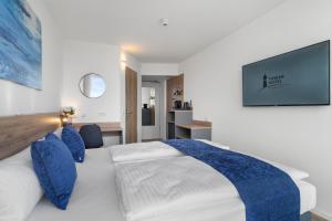 a bedroom with a white bed with blue pillows at Tower Hotel Frankfurt in Frankfurt