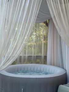 a large tub with a curtain and a window at Vikendica Cokori - private pool and jacuzzi in Banja Luka