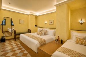 a hotel room with two beds and a chair at Abode Jaipur in Jaipur +136 photos