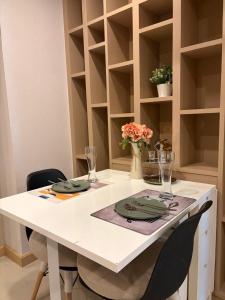 a table with chairs and a white table with plates and glasses at CONDO UNIT With BALCONY in Bangkok