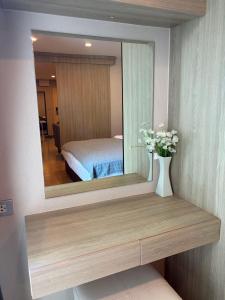 a mirror on a wall with a vase with flowers at CONDO UNIT With BALCONY in Bangkok