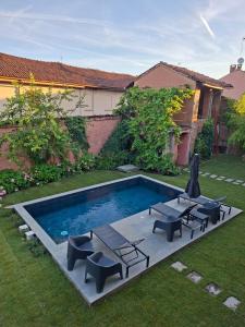 a backyard with a swimming pool with chairs and a table at Villa Lu alloggio con idromassaggio e piscina in Carignano