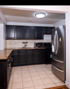 a kitchen with black cabinets and a stainless steel refrigerator at SEVENeCOZY in Edgemere