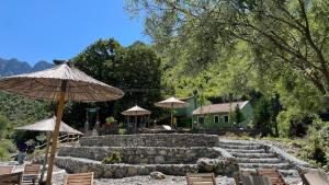 a patio with chairs and umbrellas and a house at prekal park kamping in Shkodër