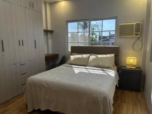 a bedroom with a white bed and a window at Casa Gutierrez in Lingayen
