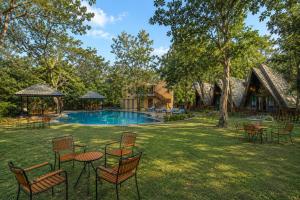 a yard with chairs and a pool and a house at Sterling Padam Pench in Khawāsa